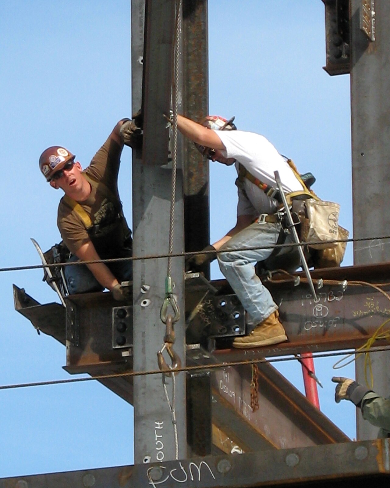Two ironworkers securing a steel beam on an active job site
